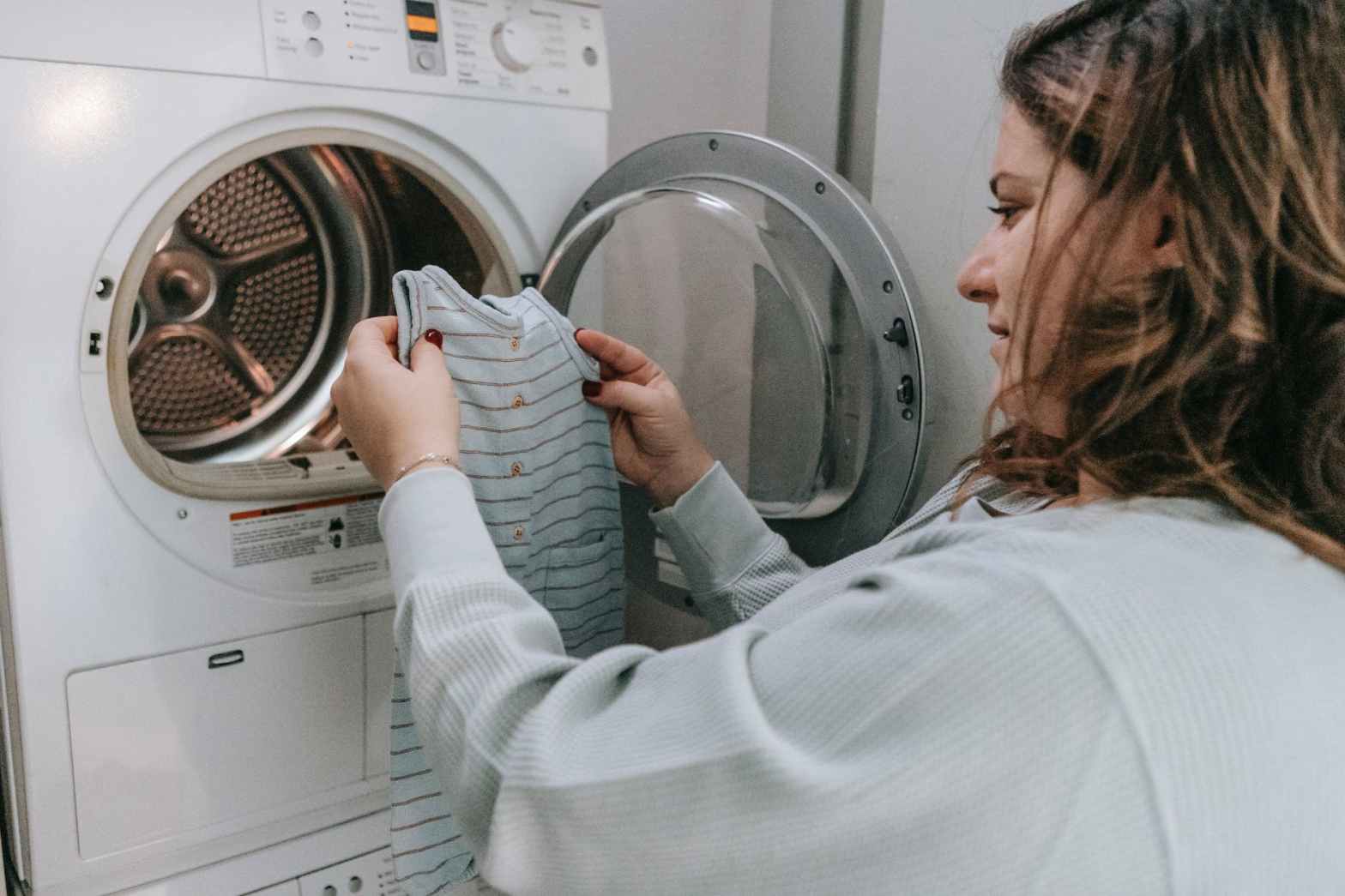 happy mother washing baby clothes in machine